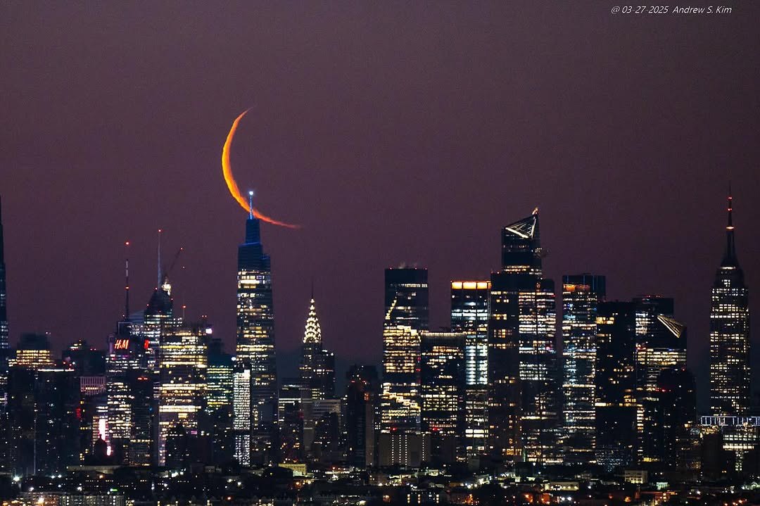 Thin crescent moon setting over the Midtown Manhattan skyline at night